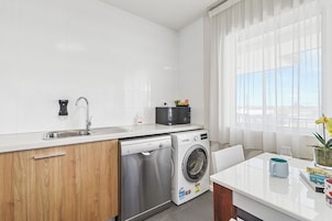 Cocina compacta con lavabo, lavadora Bosch y microondas en la encimera.