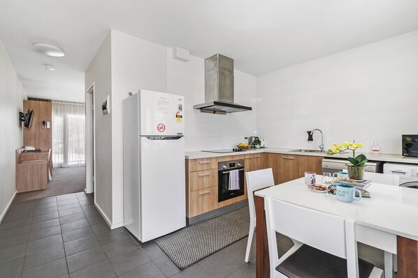 A modern kitchen with white cabinetry, a built-in oven, and a stainless steel range hood.