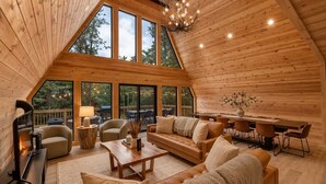 Un vaste espace de vie de style loft, doté d’un haut plafond, de grandes fenêtres, d’une table à manger en bois et d’un coin salon confortable.