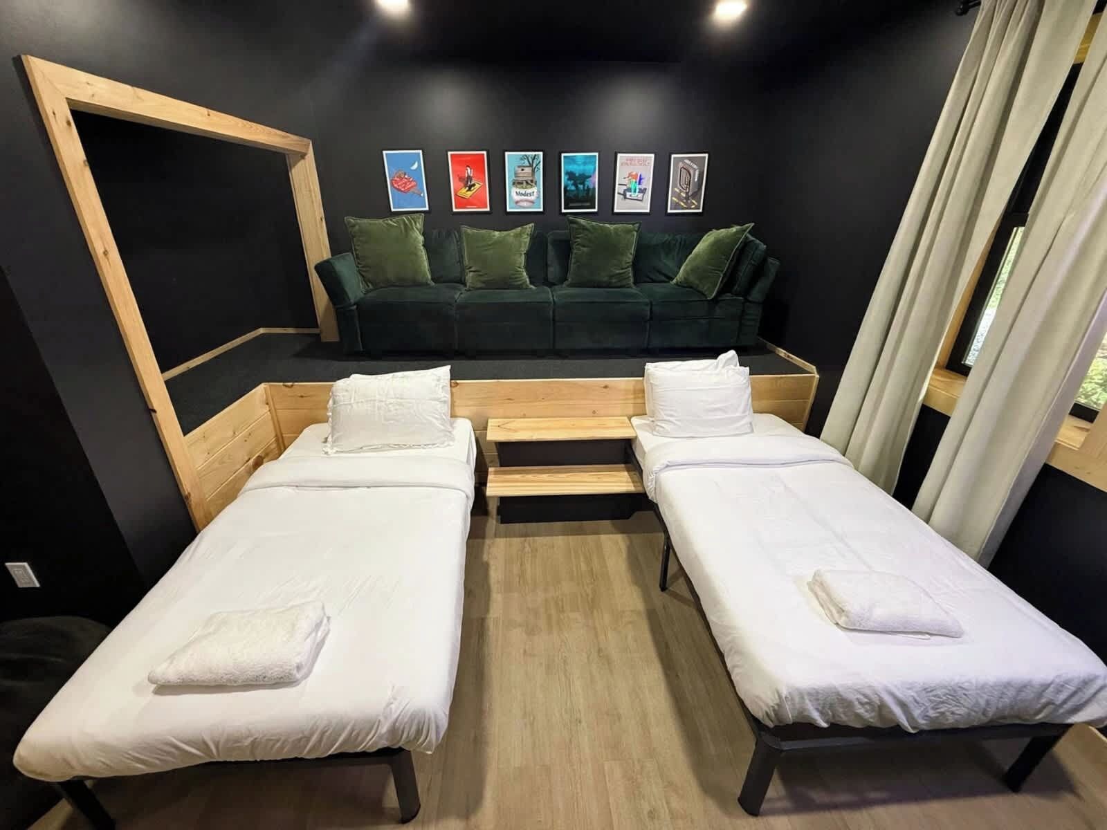 A room with two single beds, a sofa, and a wooden bench. There are framed pictures on the wall.