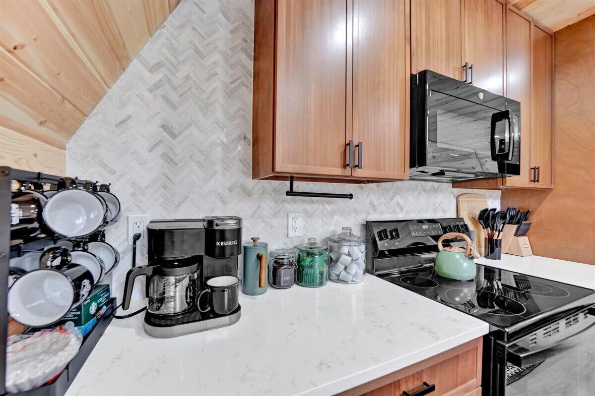 Una cocina compacta con armarios de madera, microondas, cafetera y diferentes utensilios de cocina.