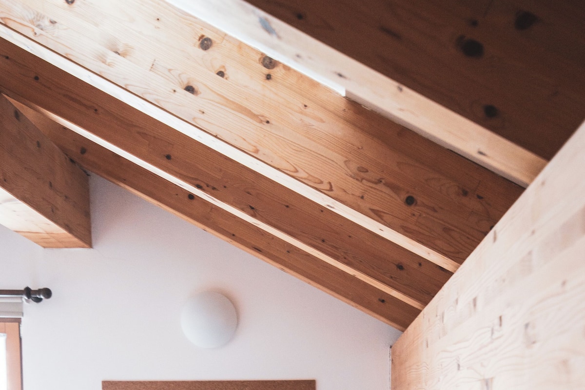 A bedroom with two wooden beds, a corkboard on the wall, and a window.