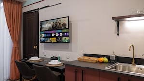 Een moderne keuken met een flatscreen televisie waarop een film draait, een spoelbak en een eethoek met stoelen en een tafel.