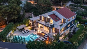 A modern two-story house with a swimming pool, outdoor seating, and a well-maintained garden.