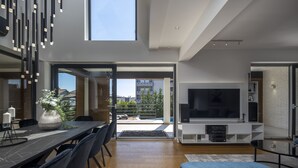 A modern living room with a large TV, a dining area with a table and chairs, and a sofa.