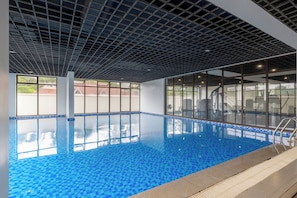 An indoor swimming pool with a tiled floor and a ceiling with a grid pattern. - Leshwa Delight by YourHost 1B Kileleshwa (Nairobi)