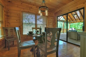 A wooden cabin interior with a dining table, chairs, and a glass-top table. - Pet-friendy, lake-front cabin rental with outdoor fireplace, dock w/Jon Boat (Ellijay)