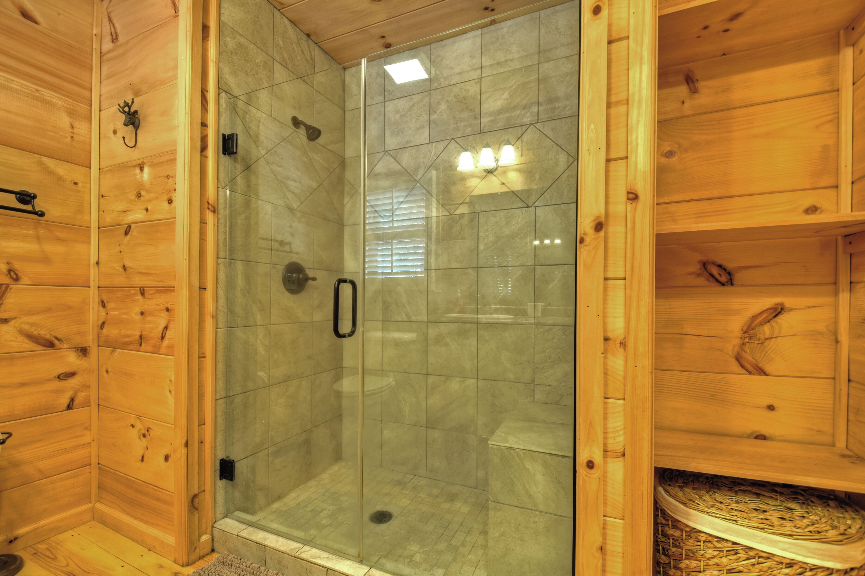 Una cabaña de madera con zona de ducha acristalada, paredes de madera y suelo de baldosas.