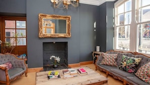 A living room with a fireplace, a sofa set, a coffee table with books, and a large mirror on the wall. - higgihaus 5 5 of 7 Rooms Monday - Friday (Cardiff)