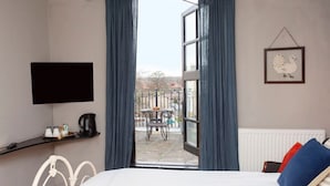 A bedroom with a bed, a TV mounted on the wall, a coffee maker, and a window with curtains. - higgihaus 5 5 of 7 Rooms Monday - Friday (Cardiff)