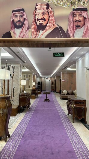 A hotel lobby with a long purple carpet, wooden furniture, and a chandelier. - Zilal Alnuzala (Makkah)