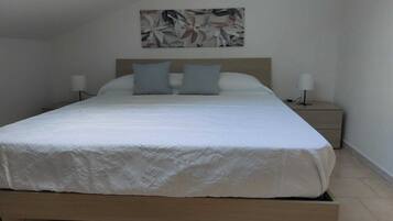 Een opgemaakt bed met een houten hoofdeinde en twee bedlampjes.