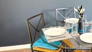 A dining area with a table set for two, chairs, and wall-mounted shelves with decorative items. - Large House | Convention Centre | 20% Discount (Harrogate)