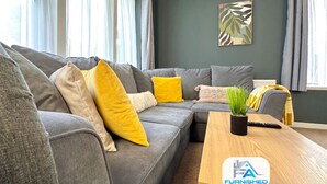 A modern living room with a sectional sofa, a coffee table, and a potted plant. - Large House | Convention Centre | 20% Discount (Harrogate)