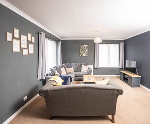 A living room with a grey sofa, a coffee table, and a TV stand.
