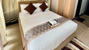 Una camera d'albergo con un letto grande, un soffitto decorativo e un armadio.