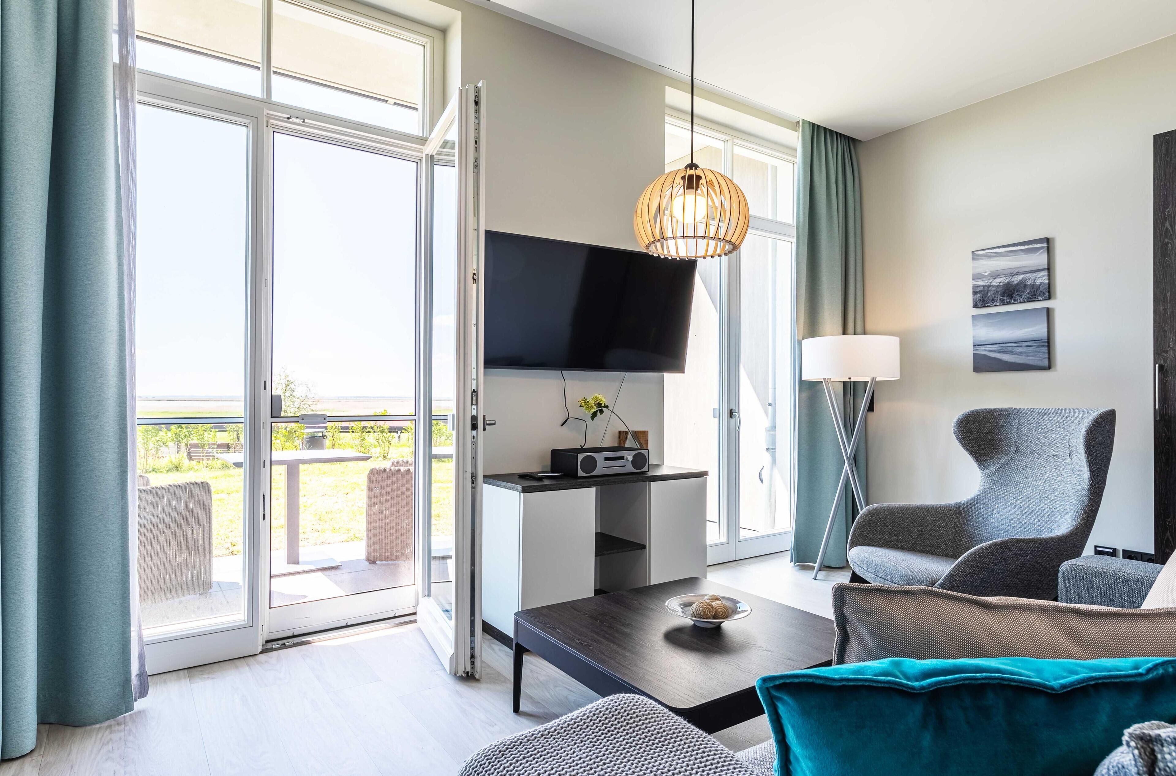 A modern living room with a flat-screen TV, a sofa, a coffee table, and a dining area with a table and chairs.