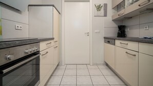 A compact kitchen with a built-in oven, a coffee maker, and a cabinet with glass doors. - Vacation apartment "Seepferdchen" with a fantastic view of the Müritz (Waren (Müritz))