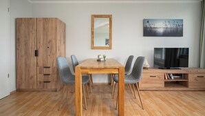 A modern living room with a wooden dining table, four chairs, a TV, and a large mirror on the wall. - Vacation apartment "Seepferdchen" with a fantastic view of the Müritz (Waren (Müritz))