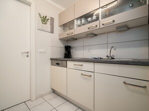 A modern kitchen with a dishwasher, a coffee maker, and a sink.