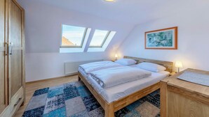 A bedroom with a skylight, a bed, a nightstand, a wooden wardrobe, and a framed picture on the wall. - "Seeblick" Vacation Rental at the Marina with a View of Lake Müritz (Waren (Müritz))