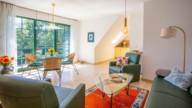 A modern living room with a sofa, chairs, a glass coffee table, and a dining area with a table and chairs. - "Kranichruh" Vacation Rental in Sembzin, Nestled in the Heart of Mecklenburg's Natural Beauty (Klink)