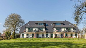 A two-story house with a balcony on the upper floor, a front door, and a lawn in front. - "Kranichruh" Vacation Rental in Sembzin, Nestled in the Heart of Mecklenburg's Natural Beauty (Klink)