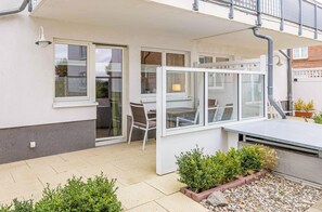 Relax in a serene outdoor space with a garden, table, and chairs under a glass enclosure.