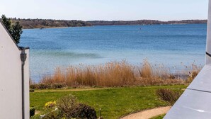 A view of a lake from a balcony with a grassy foreground and a distant shoreline. - Vacation apartment "Studio" by the lake in Waren (Müritz) (Waren (Müritz))