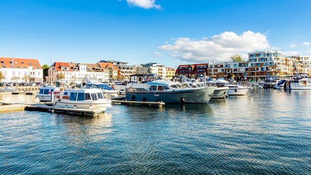 A marina with various boats docked, surrounded by multi-story buildings with balconies. - Vacation apartment "Studio" by the lake in Waren (Müritz) (Waren (Müritz))