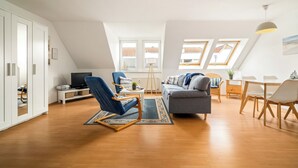 A modern apartment with a loft-style ceiling, a dining area, a living room with a sofa and armchair, and a television. - Vacation apartment "Studio" by the lake in Waren (Müritz) (Waren (Müritz))