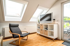 Una sala de estar moderna con un televisor, una silla y un estante blanco.