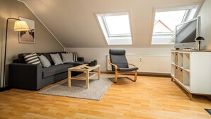 A modern living room with a sofa, armchair, coffee table, TV, and a picture on the wall. - Vacation apartment "MüritzLounge" in Waren (Müritz) (Waren (Müritz))