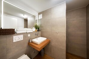 A modern bathroom with a wooden vanity, a white sink, a large mirror, and a potted plant. - Vacation apartment "MüritzLounge" in Waren (Müritz) (Waren (Müritz))