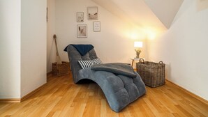 A cozy room with a curved bed, a small table with a lamp, and a wall with framed pictures. - Vacation apartment "MüritzLounge" in Waren (Müritz) (Waren (Müritz))