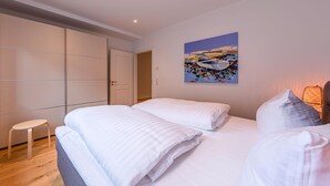 A bedroom with two beds, a small stool, a wardrobe, and a painting on the wall. - "Inselpirat" Vacation Rental in the Island Town of Malchow (Malchow)