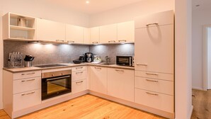 A modern kitchen with white cabinets, a built-in oven, a microwave, and a coffee maker. - "Inselpirat" Vacation Rental in the Island Town of Malchow (Malchow)