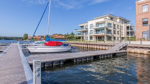 A marina with a dock, a sailboat, and a modern building with balconies. - "Inselpirat" Vacation Rental in the Island Town of Malchow (Malchow)
