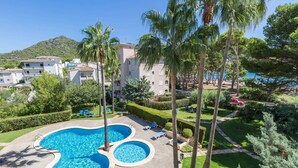 A resort with a large swimming pool, palm trees, and a view of the sea. - Oro Del Mar Iv Apartamento O2 - Apartment (Canyamel - Capdepera, Illes Balears)