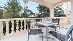 A balcony with a table and chairs, surrounded by greenery and buildings. - Oro Del Mar Iv Apartamento O2 - Apartment (Canyamel - Capdepera, Illes Balears)