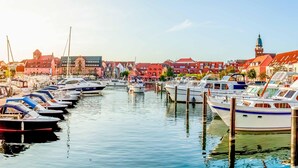 Een jachthaven met boten afgemeerd langs een rustig water, omringd door gebouwen met verschillende architectuurstijlen.