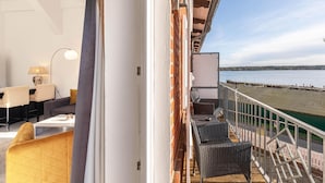 Un balcone con mobili in vimini, una parete bianca e vista sull'acqua.