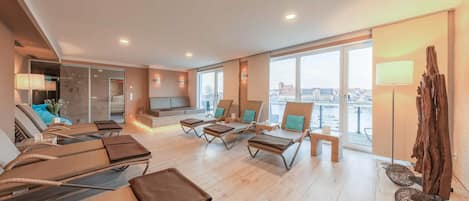 A modern hotel lobby with lounge chairs, a seating area, and large windows offering a city view.