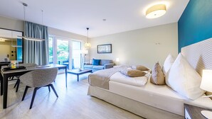 Ein modernes Hotelzimmer mit einer Couch, einem Esstisch und einer Küchenzeile.