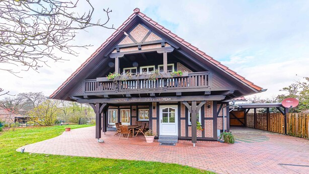 A two-story house with a balcony, a brick pathway, and a wooden deck. - "Havelquelle" Vacation Home in Kratzeburg, surrounded by beech forests and lakes (Kratzeburg)