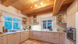 A kitchen with wooden cabinets, a stove, and a window with lace curtains. - "Havelquelle" Vacation Home in Kratzeburg, surrounded by beech forests and lakes (Kratzeburg)