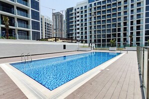Une piscine rectangulaire dont le bord est recouvert de carreaux, entourée d’une terrasse également carrelée.