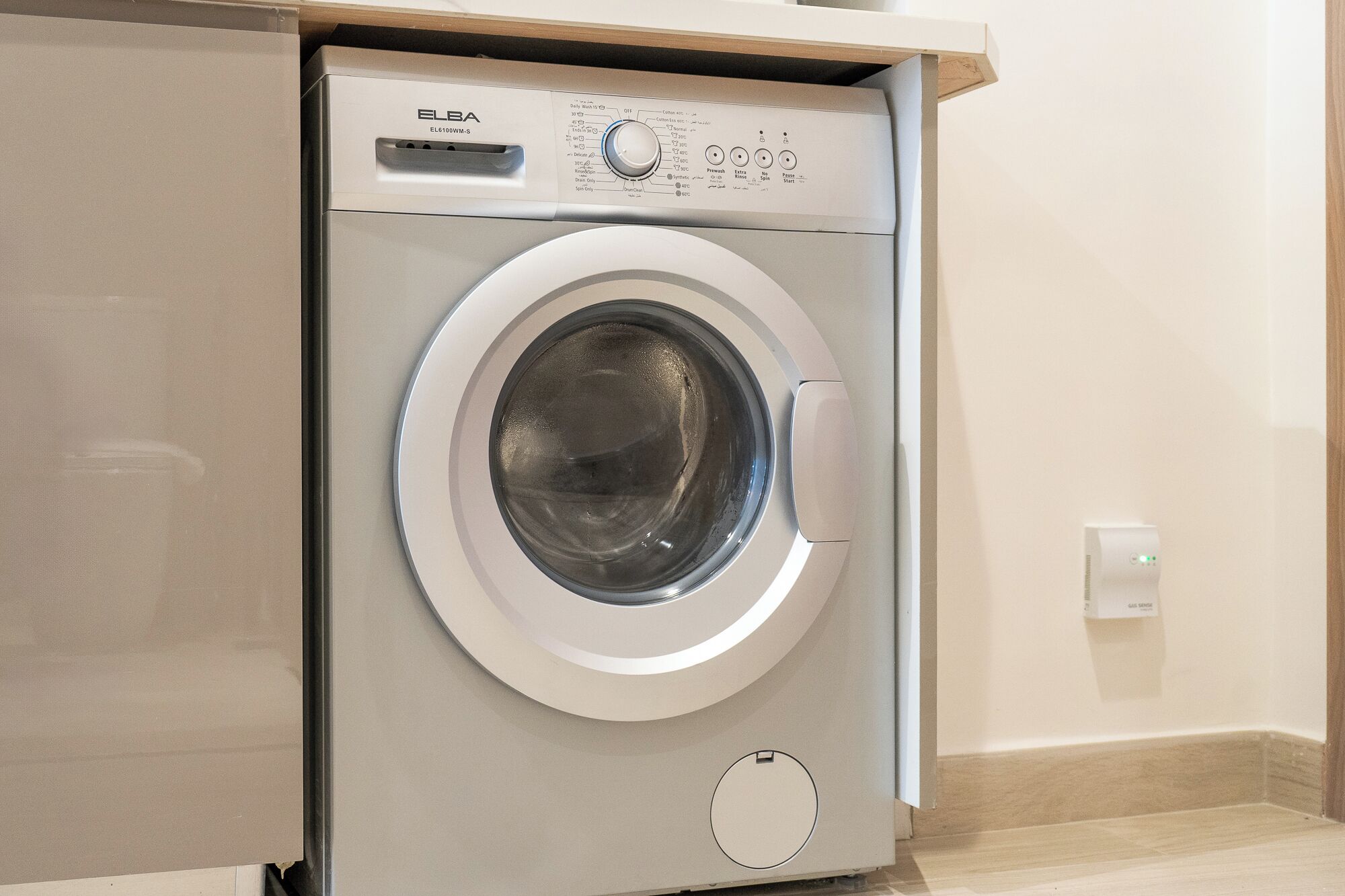 A front-loading washing machine with a control panel, a door, and a control knob.