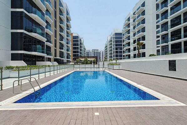 Une piscine moderne entourée d’immeubles d’habitation de grande hauteur.