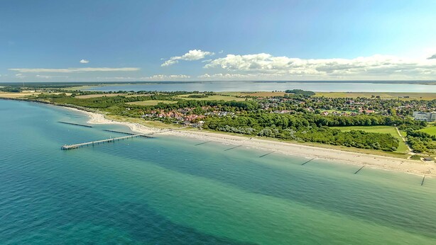 An aerial view of a coastal town with a pier extending into the sea, surrounded by greenery and residential areas. - 5 star apartment Strandräuber with sea view in Wustrow (Wustrow)